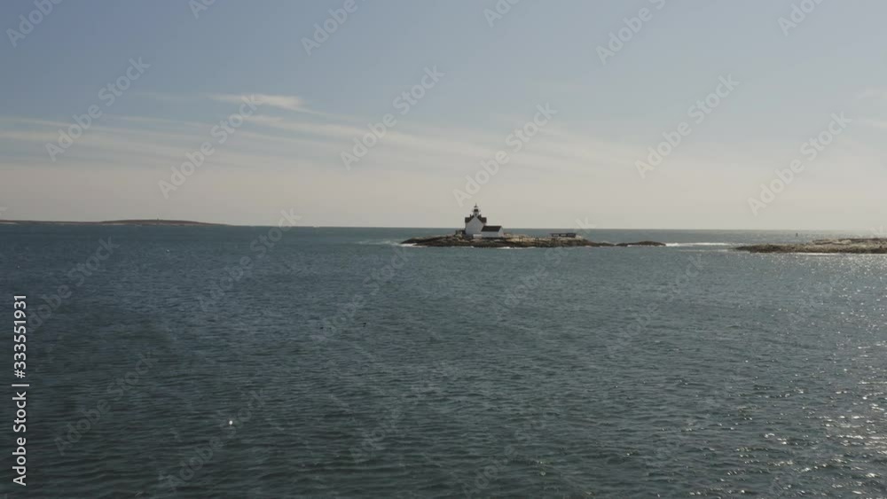 Waves lapping a small rocky island with a white lighthouse, coast of maine, Aerial Waves lapping a small rocky island with a white lighthouse, coast of maine, Aerial