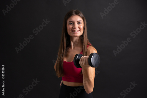 Young sport woman making weightlifting over isolated black background