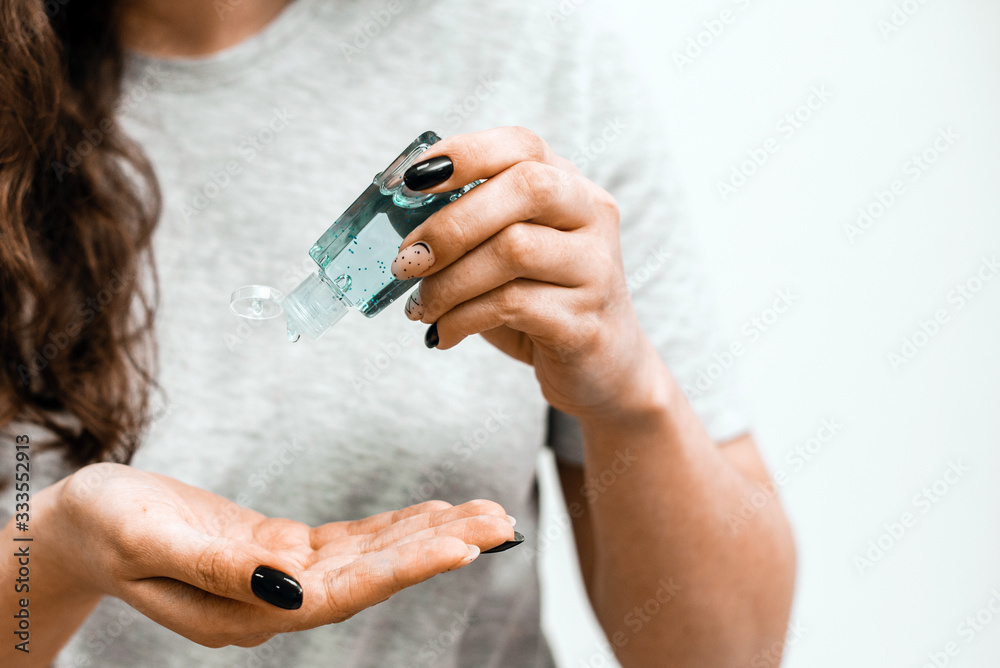 Close up view of woman person using small portable antibacterial hand sanitizer on hands. Woman with antibacterial antiseptic gel for hands disinfection and health protection prevention during flu