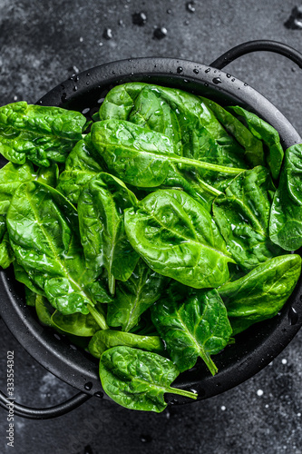 Fresh spinach leaves in a colander. Black background. Top view