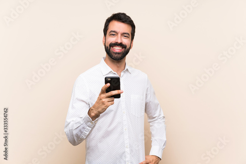 Young man with beard holding a mobile sending a message with the mobile © luismolinero