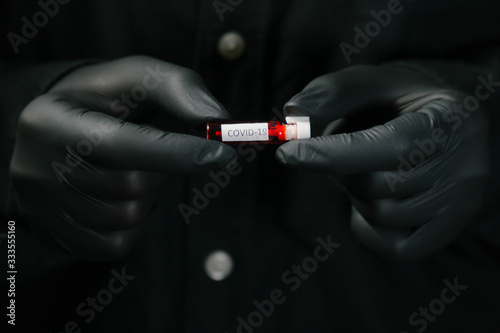 Closeup of microbiologist or medical worker hand with black surgical gloves new rapidly spreading Coronavirus COVID-19 