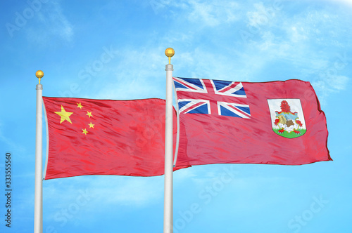 China and Bermuda two flags on flagpoles and blue cloudy sky photo