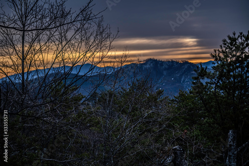 mountain sunrise with tree branches in the foreground © STANLEY