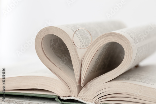 Pages of book are twisted as a heart sign with gold ring