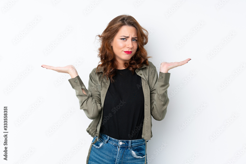 Young Russian woman over isolated white background having doubts while raising hands Young Russian woman over isolated white background having doubts while raising hands