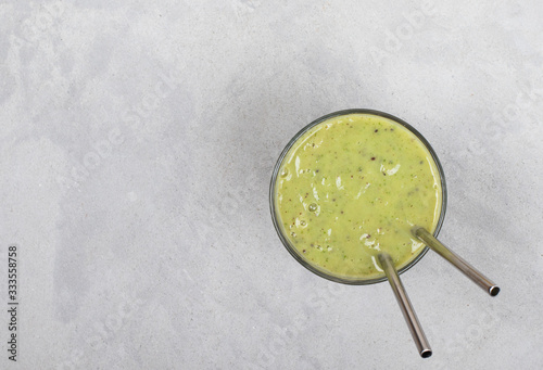 Vegan drink smoothie from kiwi, banana and rucola in a glass on a light background top view