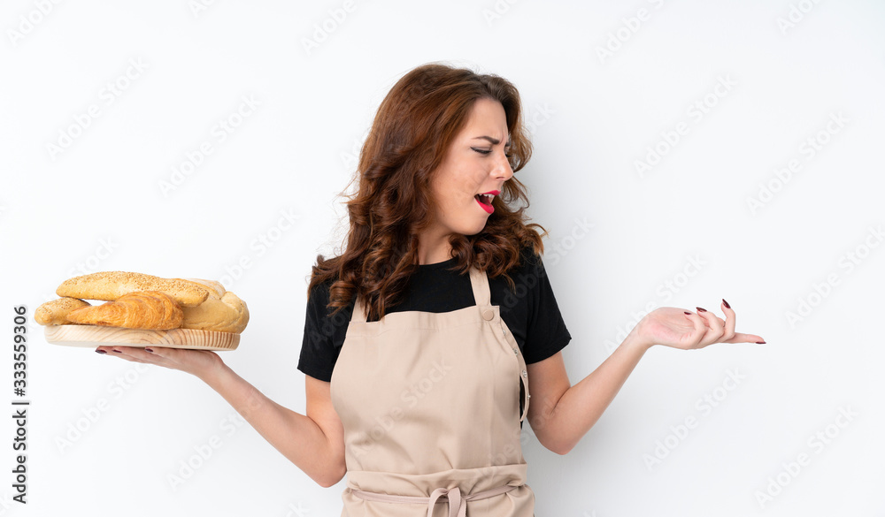 Woman in chef uniform. Female baker holding a table with several breads with surprise facial expression Woman in chef uniform. Female baker holding a table with several breads with surprise facial expression