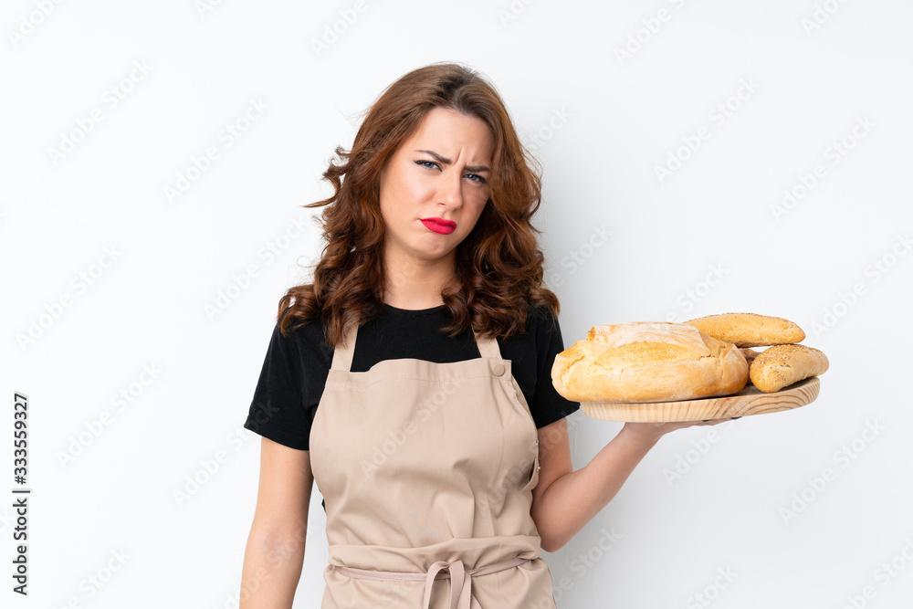 Woman in chef uniform. Female baker holding a table with several breads with sad expression Woman in chef uniform. Female baker holding a table with several breads with sad expression