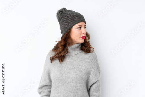 Young Russian woman with winter hat over isolated white background looking side