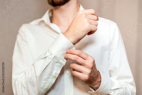 Guy straightens a cufflink on a shirt sleeve
