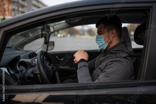 A man sits car and washes his hands with antiseptic gel. healthcare concept in car. The mask is white on the face. coronavirus, disease, infection, quarantine, covid-19