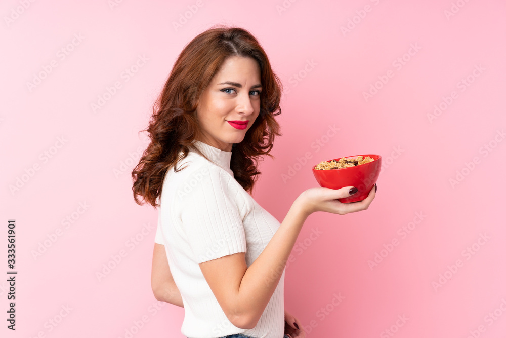 Young Russian woman over isolated pink background holding a bowl of cereals Young Russian woman over isolated pink background holding a bowl of cereals