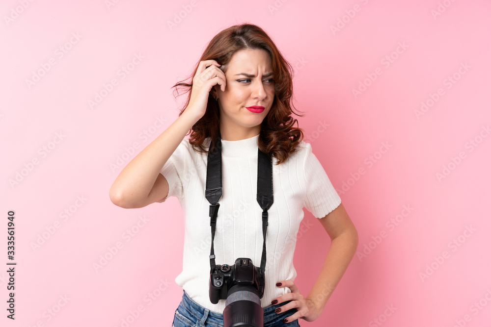 Young Russian woman over isolated pink background with a professional camera and thinking