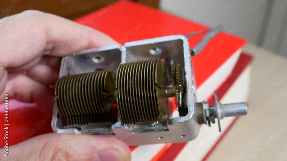 Male hand turning the rotor of a tube radio capacitor for station