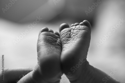 Newborn baby feet close up showing the creases and wrinkles on the soles of the feet. Black and white photo. Macro photo of tiny newborn baby feet.  