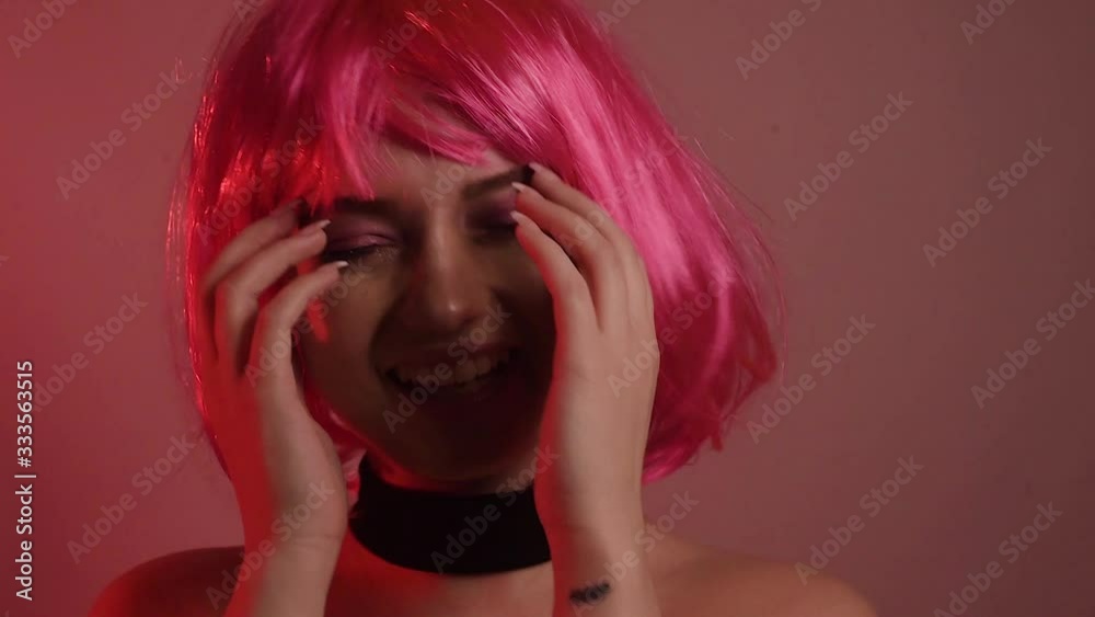 Girl with pink short hair. A model with long pink earrings and makeup. The girl in the video laughs, flirts, poses, dances, touches her hair, goes crazy. Fashion video portrait Girl with pink short hair. A model with long pink earrings and makeup. The girl in the video laughs, flirts, poses, dances, touches her hair, goes crazy. Fashion video portrait