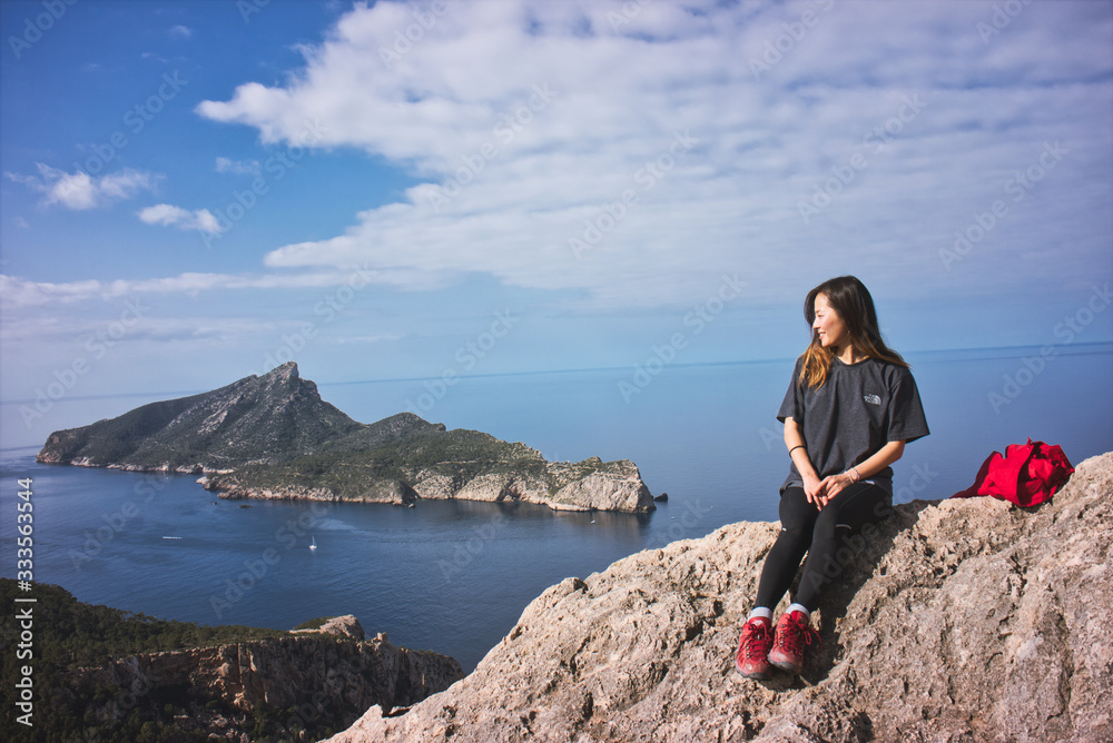 Beautiful young woman going for trekking and looking to the dragonera island in the mediterranean sea