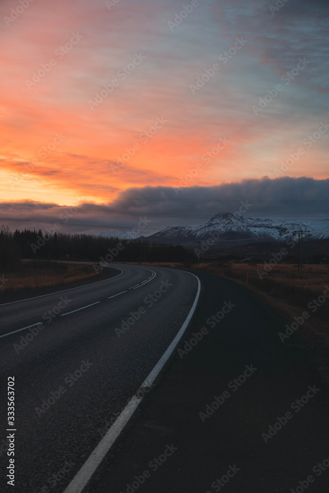 Sunrise in a curved road in Iceland with mountain backdrop and vibrant skies
