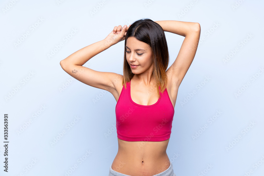 Young sport woman over isolated blue background stretching