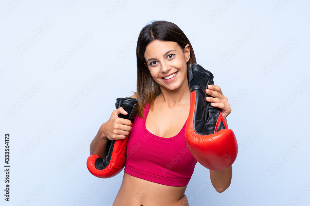 Young sport woman over isolated blue background with boxing gloves Young sport woman over isolated blue background with boxing gloves