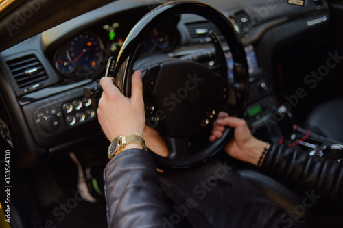 Hands on the steering wheel, a man drives a car. Learning to drive. Expensive car. Traveling.