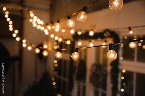 Luminous incandescent lamps hang in the form of a garland on wires, against the background of a shop window. Background from a garland. Incandescent lamps.