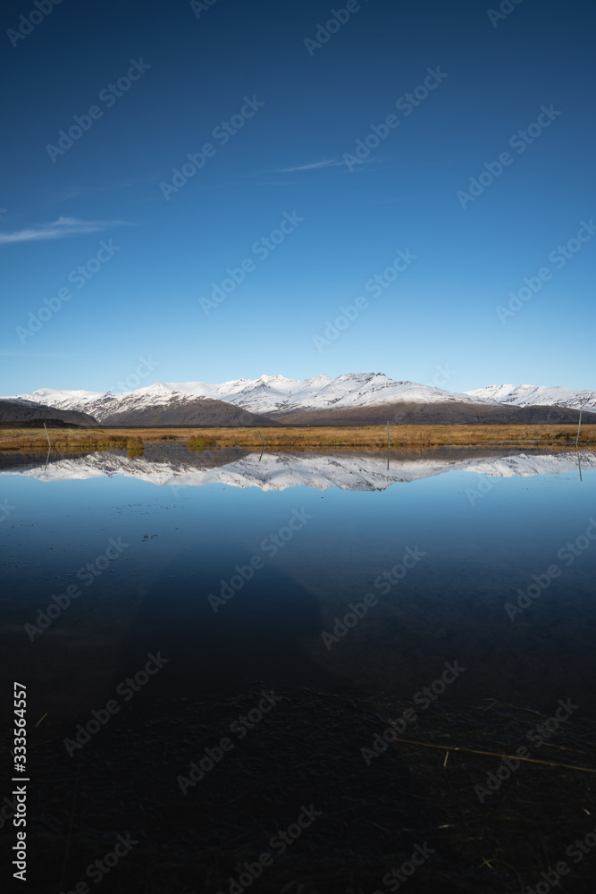Snow Covered Mountain Landscape in Iceland with reflection in the water 