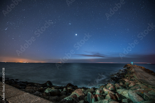 Fototapeta Naklejka Na Ścianę i Meble -  Long exposure of Baltic sea with scenic colorful sunset. Silky water motion and breakwater with huge rocks. 