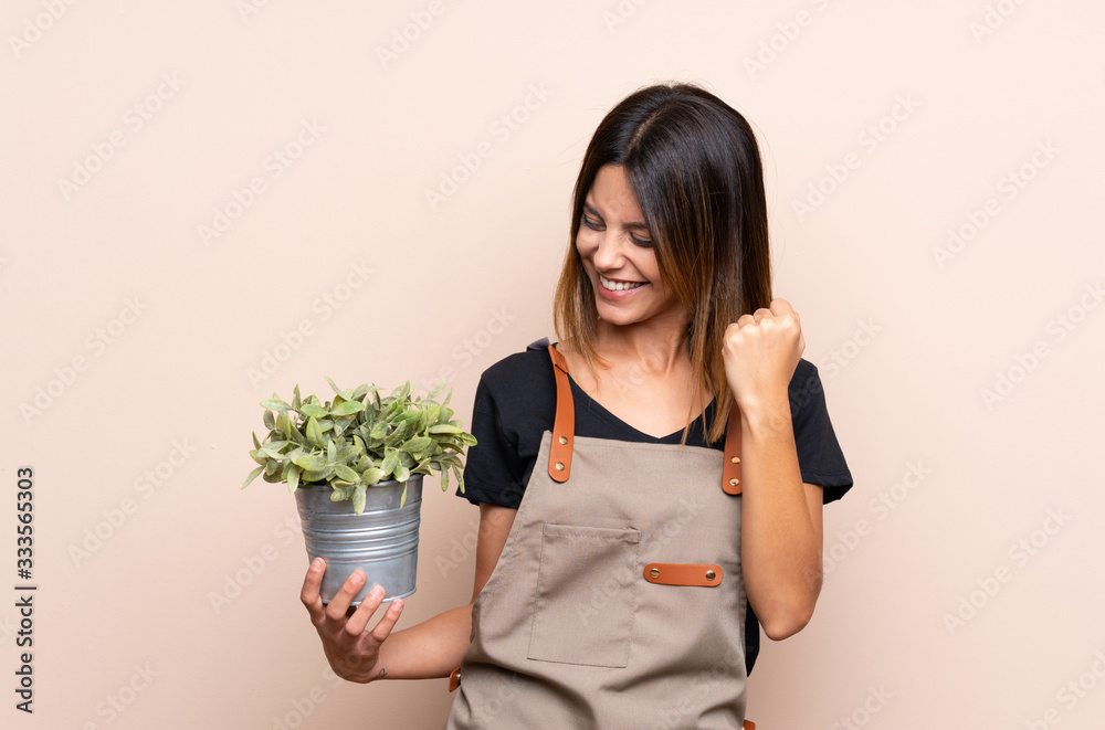 Young woman holding a plant celebrating a victory Young woman holding a plant celebrating a victory