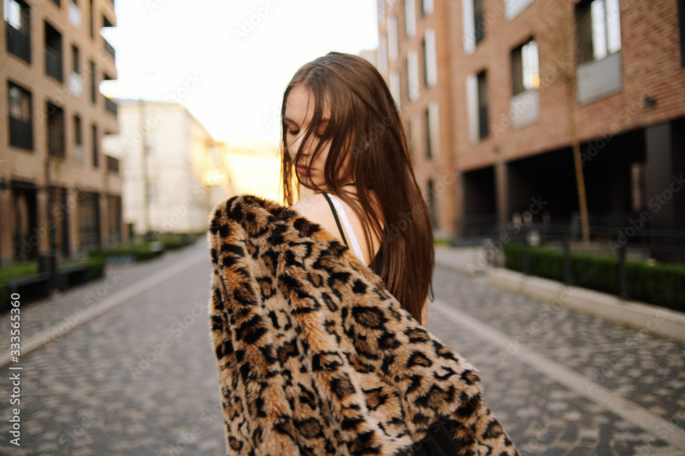 Gorgeous girl walks about the city. Brunette with long hair in a black dress and a leopard cape. Girl, fashion photo, street fashion. Fashionable girl walks in the city of Europe, travels.
