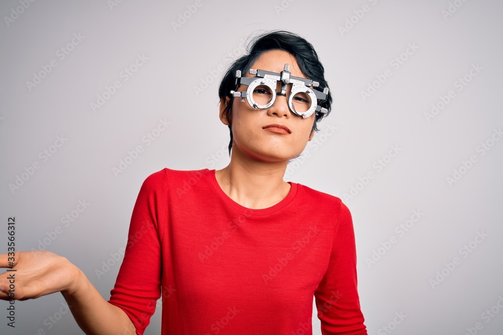 Young beautiful asian girl wearing optometry glasses standing over isolated white background clueless and confused expression with arms and hands raised. Doubt concept. Young beautiful asian girl wearing optometry glasses standing over isolated white background clueless and confused expression with arms and hands raised. Doubt concept.