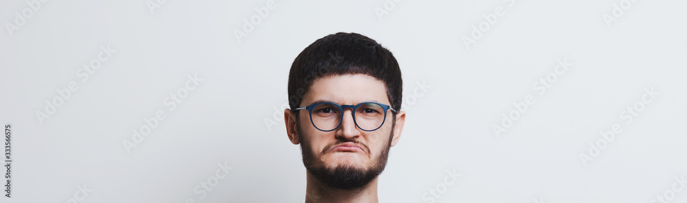 Portrait of confident young man showing thumbs up, over white background. Wearing glasses and grey sweater. Portrait of confident young man showing thumbs up, over white background. Wearing glasses and grey sweater.