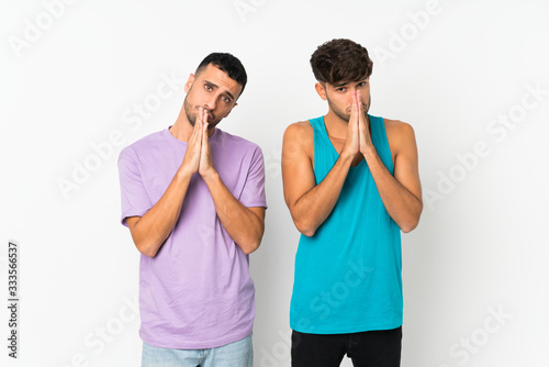 Two men over isolated background keeps palm together. Person asks for something
