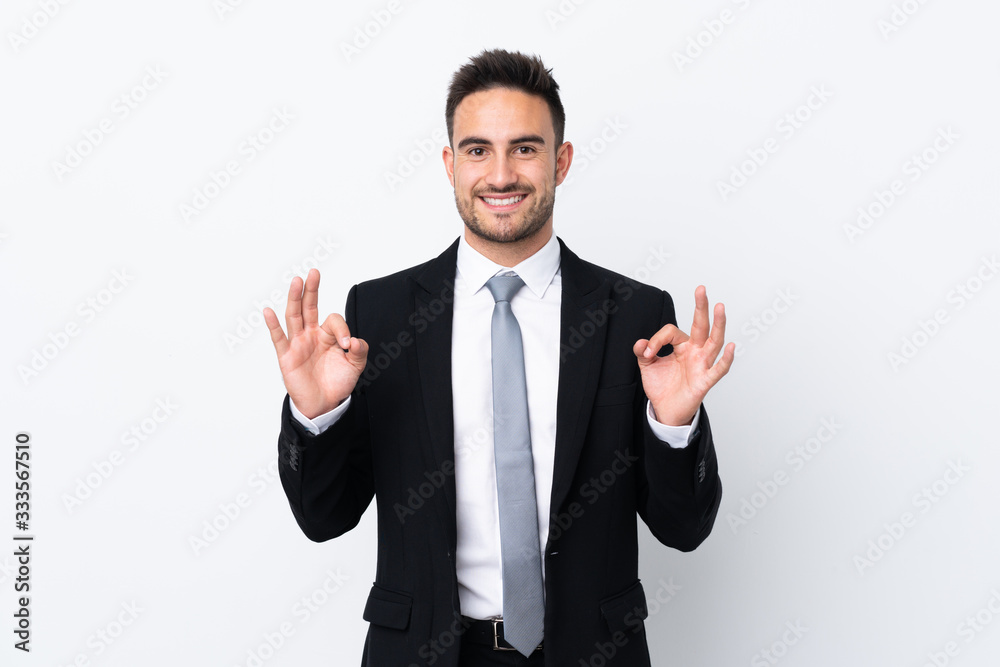 Young business man over isolated background showing an ok sign with fingers Young business man over isolated background showing an ok sign with fingers