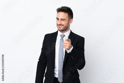 Young business man over isolated background points finger at you