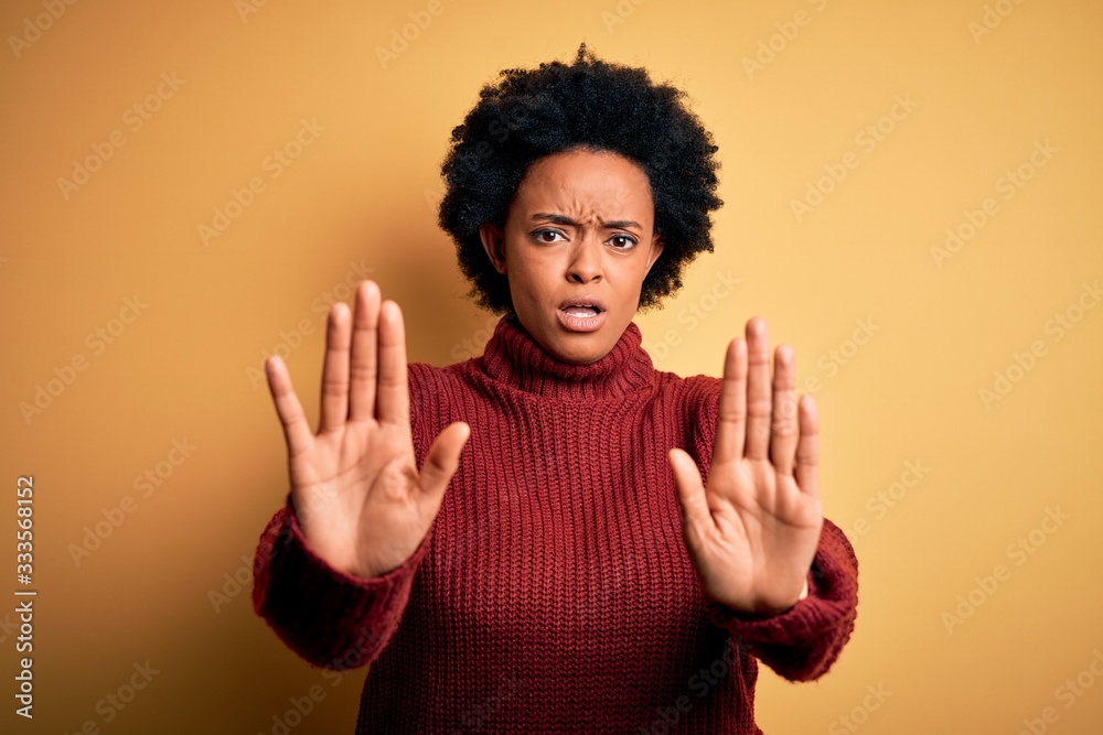 Young beautiful African American afro woman with curly hair wearing casual turtleneck sweater doing stop gesture with hands palms, angry and frustration expression Young beautiful African American afro woman with curly hair wearing casual turtleneck sweater doing stop gesture with hands palms, angry and frustration expression
