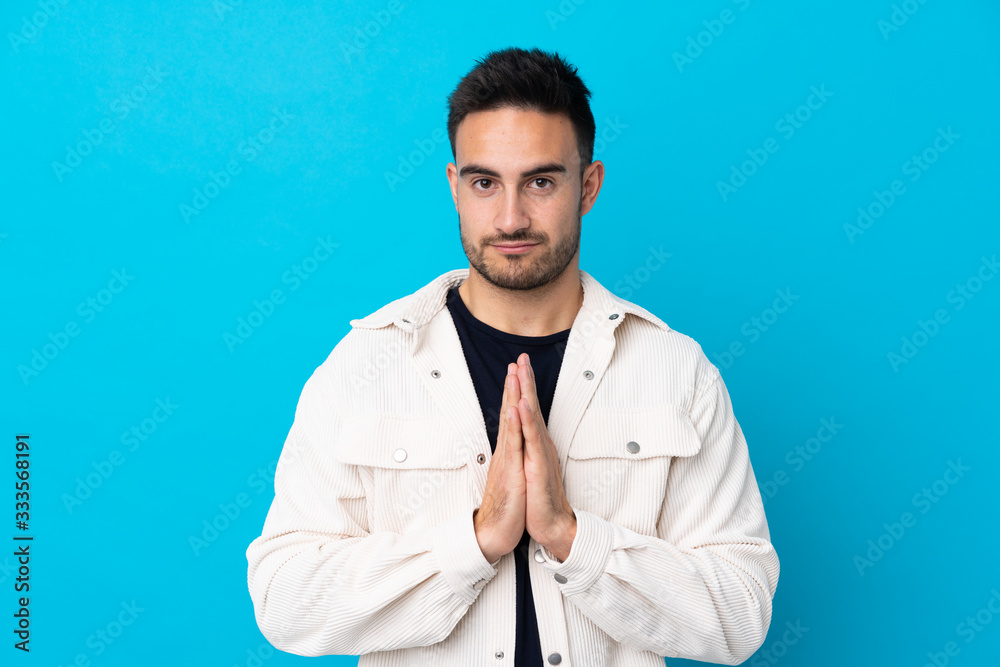 Young handsome man over isolated blue background pleading Young handsome man over isolated blue background pleading