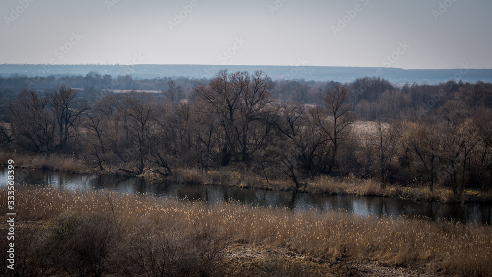 A quiet river in a green rural area. Beautiful landscape with a river with calm water, located next to a spring forest in nature A quiet river in a green rural area. Beautiful landscape with a river with calm water, located next to a spring forest in nature