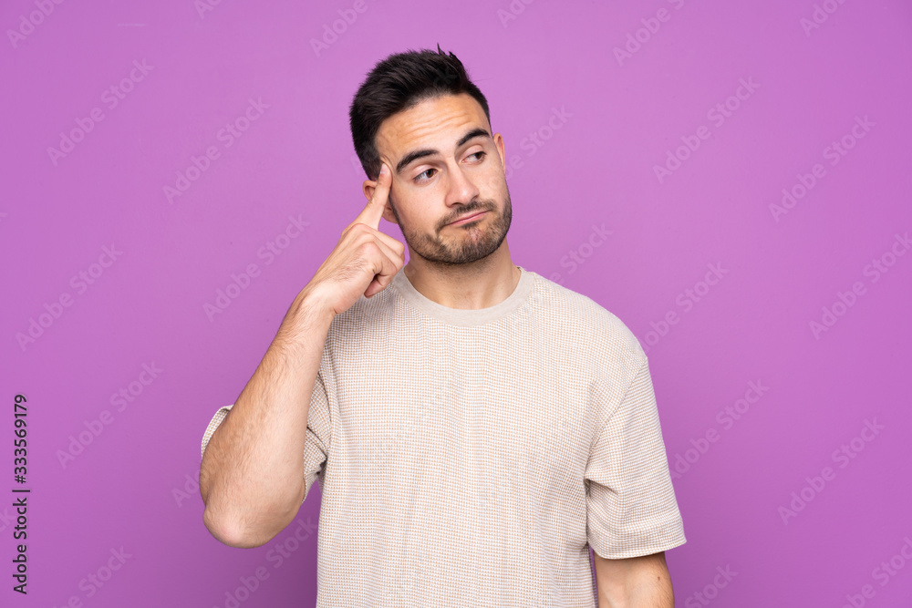 Young handsome man over isolated purple background making the gesture of madness putting finger on the head Young handsome man over isolated purple background making the gesture of madness putting finger on the head