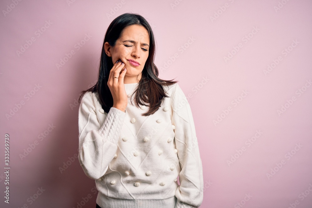 Young brunette woman with blue eyes wearing casual sweater over isolated pink background touching mouth with hand with painful expression because of toothache or dental illness on teeth. Dentist Young brunette woman with blue eyes wearing casual sweater over isolated pink background touching mouth with hand with painful expression because of toothache or dental illness on teeth. Dentist