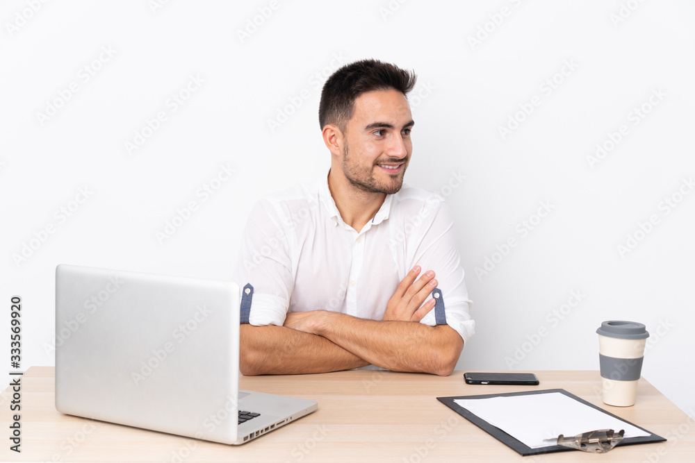 Young business man with a mobile phone in a workplace laughing Young business man with a mobile phone in a workplace laughing