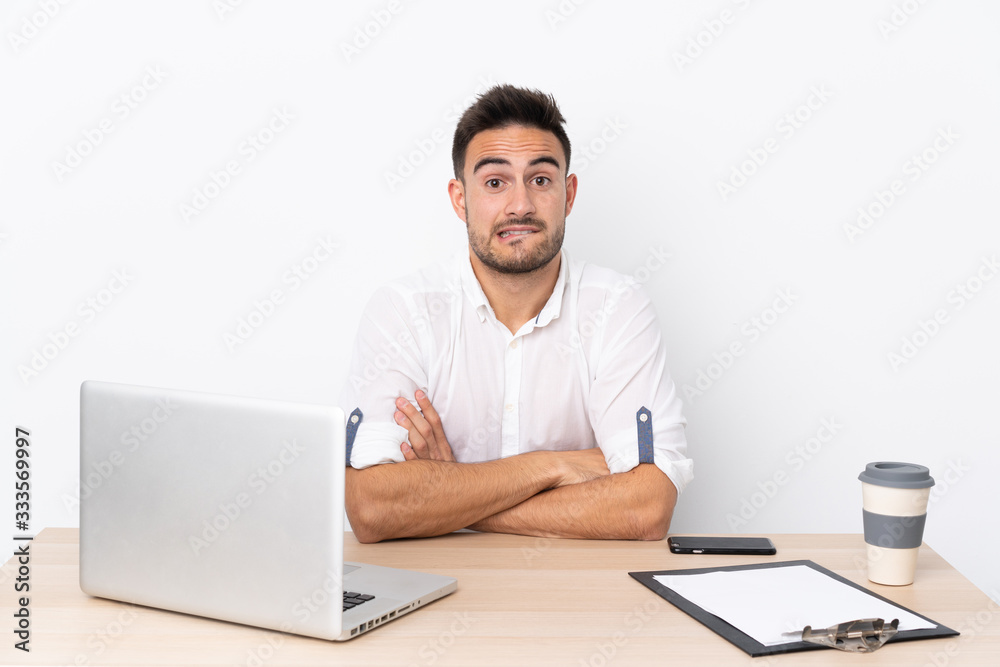 Young business man with a mobile phone in a workplace having doubts and with confuse face expression Young business man with a mobile phone in a workplace having doubts and with confuse face expression