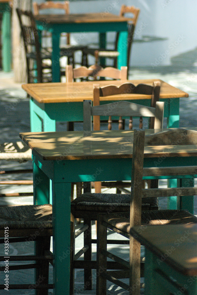 Taverna tables and chairs at a traditional Greek restaurant on the island of Folegandros.  Sunlight and shade in the late afternoon.