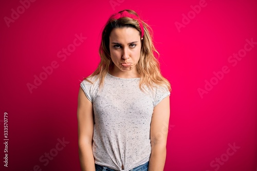 Young beautiful blonde woman wearing casual t-shirt standing over isolated pink background depressed and worry for distress, crying angry and afraid. Sad expression.