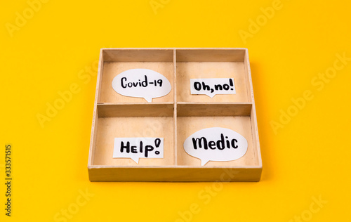 Plywood box with four compartments in which lie different paper clouds of messages with the text coronavirus disease. The concept of maintaining health during the coronavirus epidemic