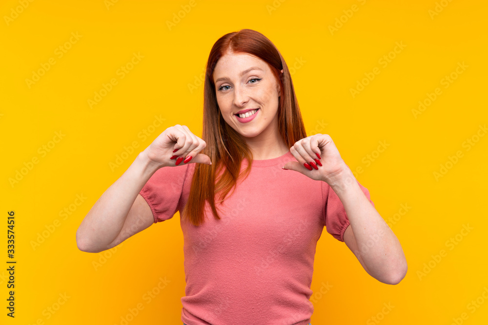 Young redhead woman over isolated yellow background proud and self-satisfied Young redhead woman over isolated yellow background proud and self-satisfied