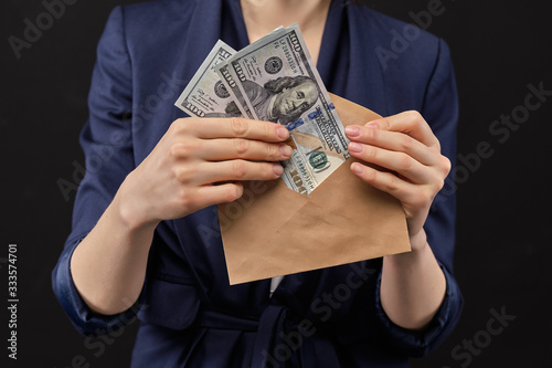 Girl in a jacket removes us dollars into an envelope on a black background.