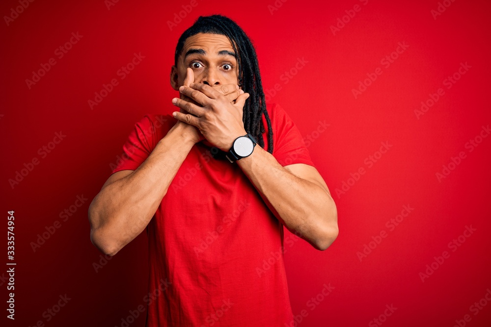 Young handsome african american afro man with dreadlocks wearing red casual t-shirt shocked covering mouth with hands for mistake. Secret concept. Young handsome african american afro man with dreadlocks wearing red casual t-shirt shocked covering mouth with hands for mistake. Secret concept.