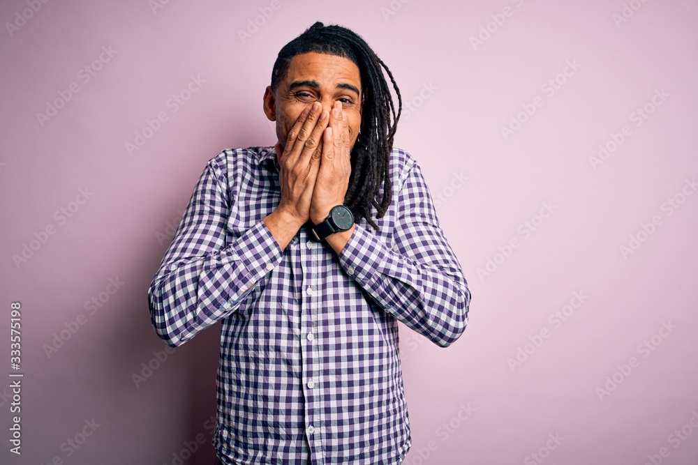 Young handsome african american afro man with dreadlocks wearing casual shirt laughing and embarrassed giggle covering mouth with hands, gossip and scandal concept Young handsome african american afro man with dreadlocks wearing casual shirt laughing and embarrassed giggle covering mouth with hands, gossip and scandal concept